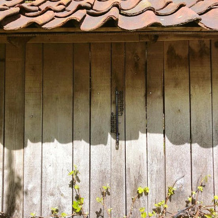 Thermometer aan houten schutting met dakpannen