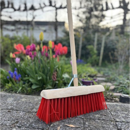 Nylon bezem op stenen ondergrond met bloemen