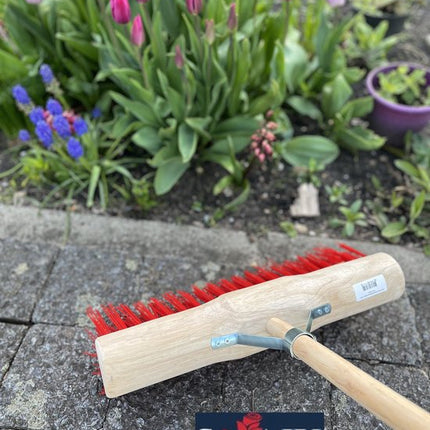 Buitenbezem op stenen pad met bloemen op achtergrond